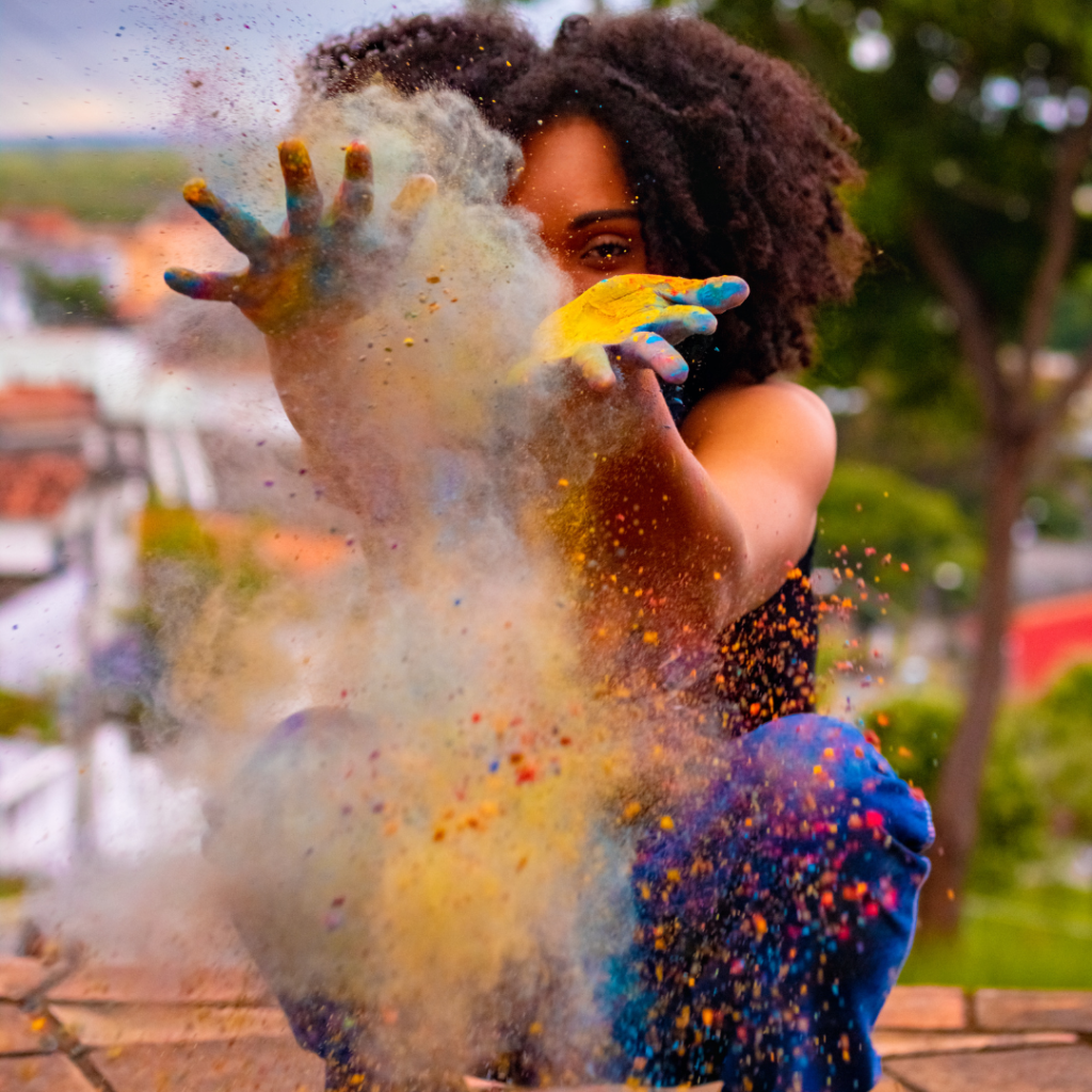 Woman kneeling and throwing colored powder in the air